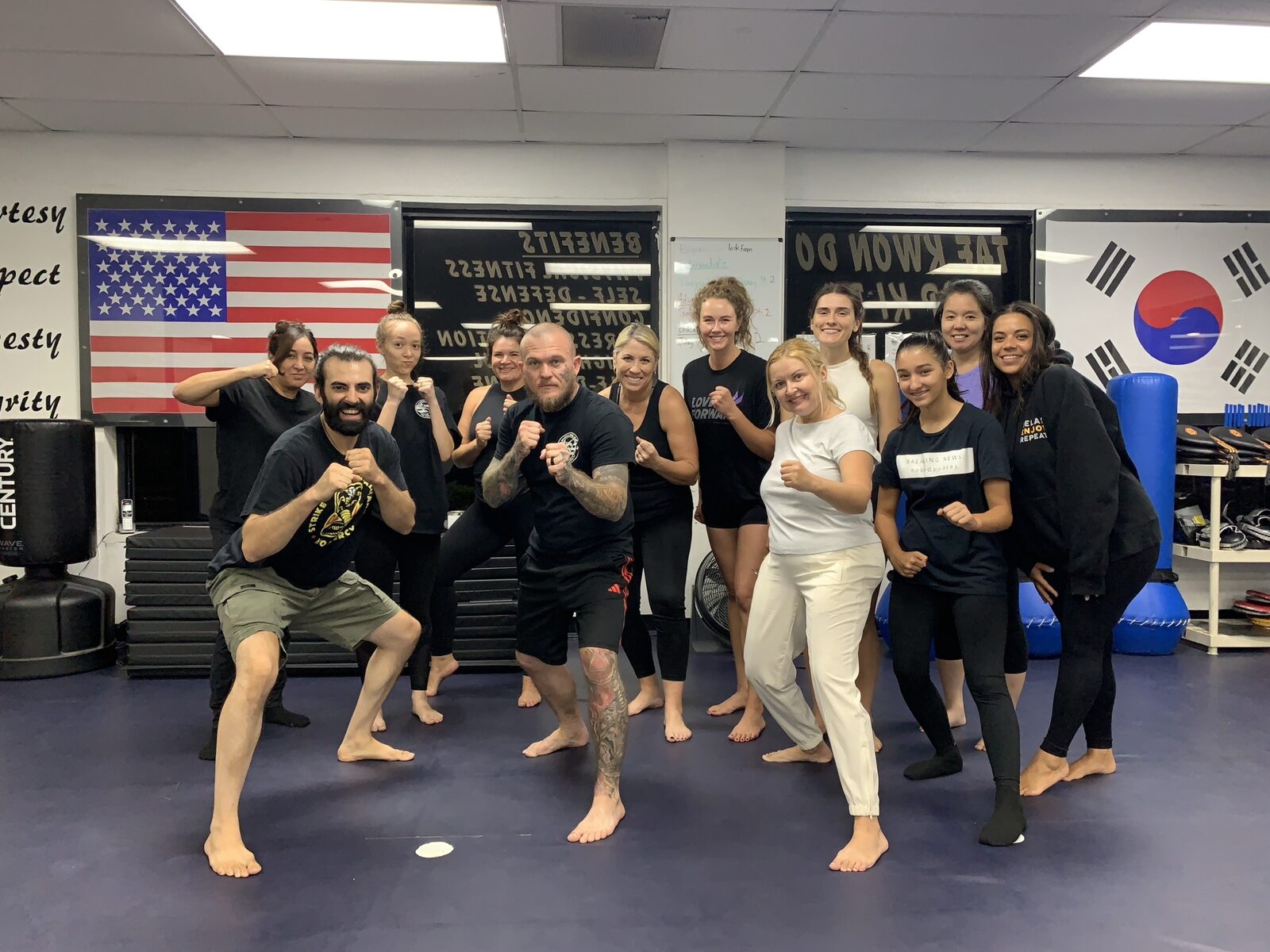 Group of students and instructors posing in fighting stances in the dojo